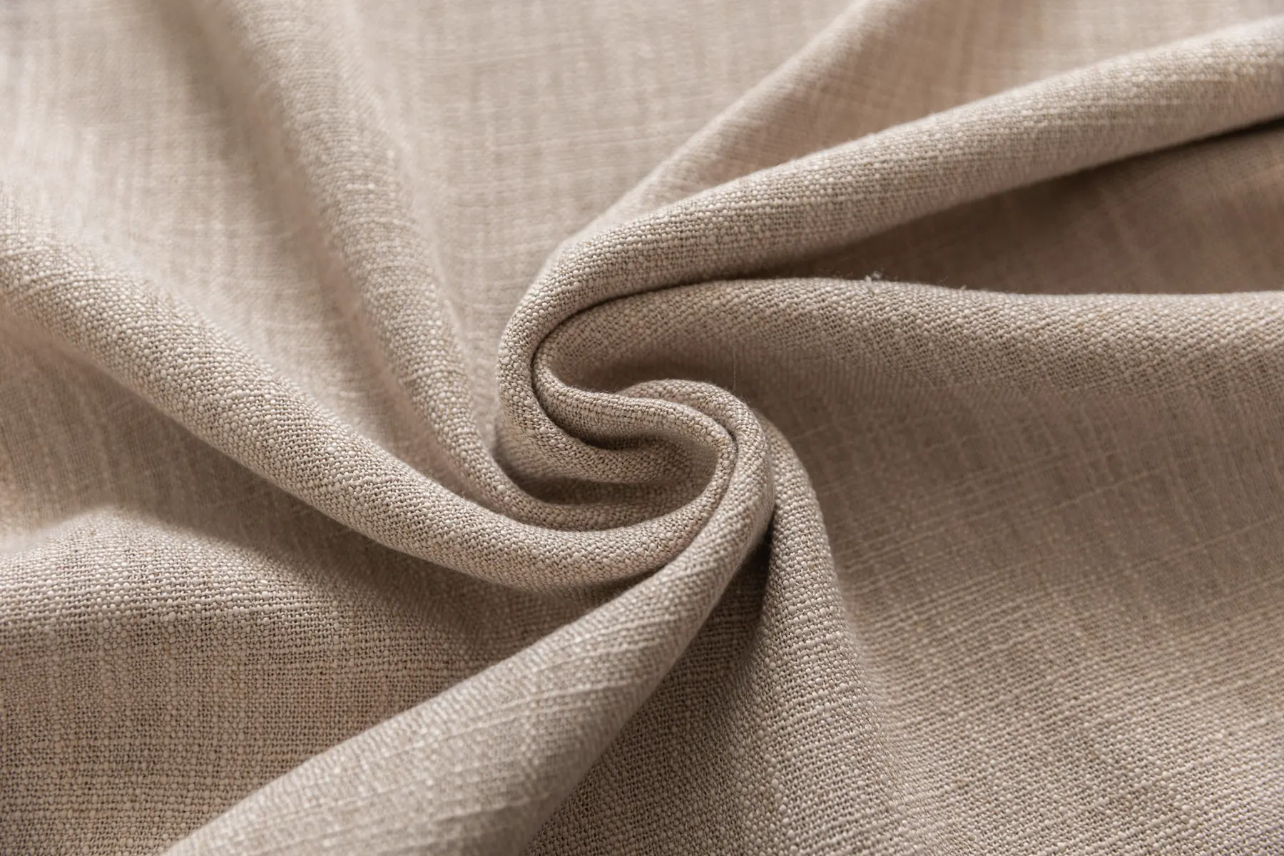 Beige woven cloth folded into a soft swirl, the weave visible across every fold